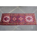 A Persian red ground Heritz runner with a starburst medallion design, 46" x 131"