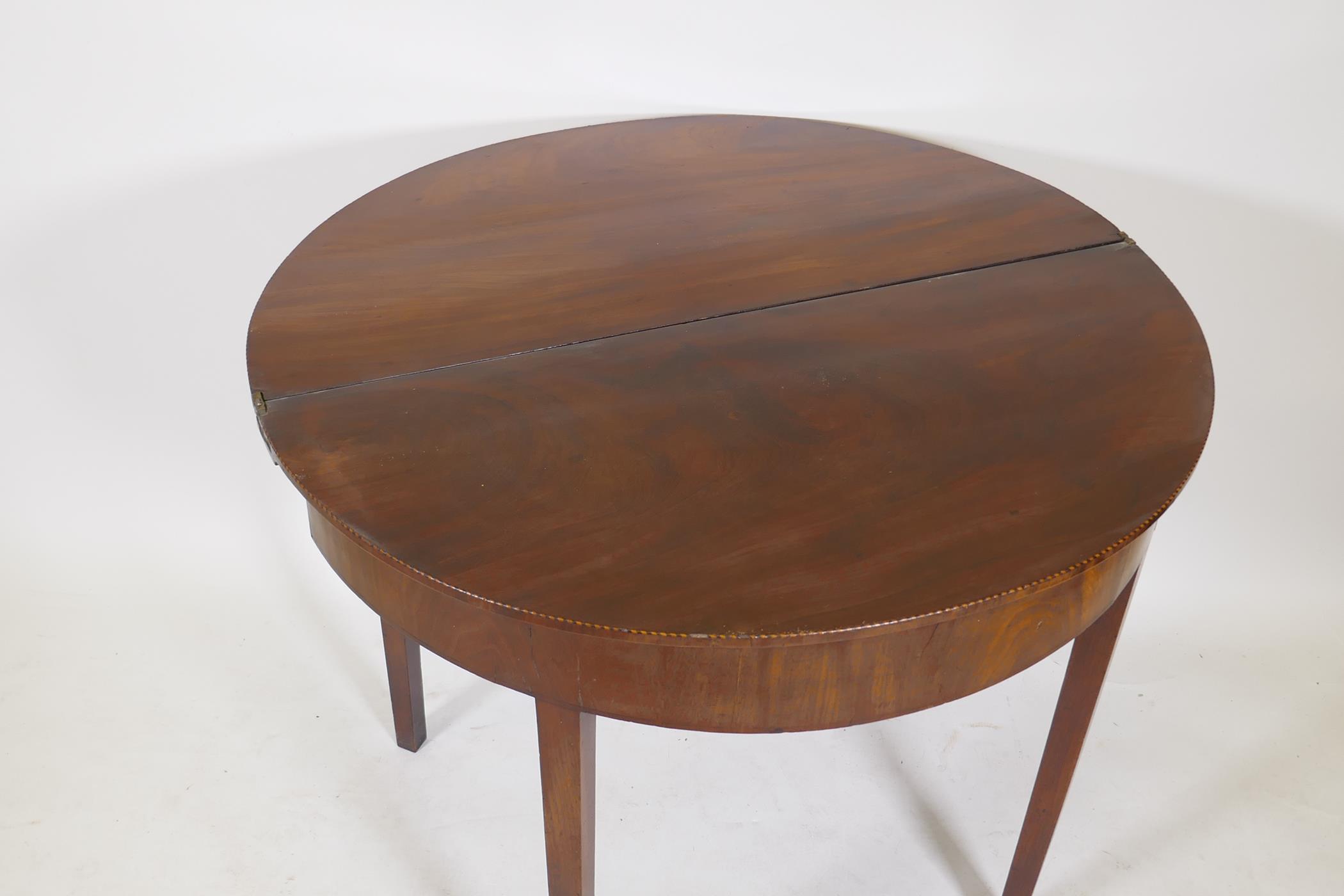 A Georgian mahogany fold over demi lune tea table with inlaid edges, raised on square tapering - Image 3 of 4