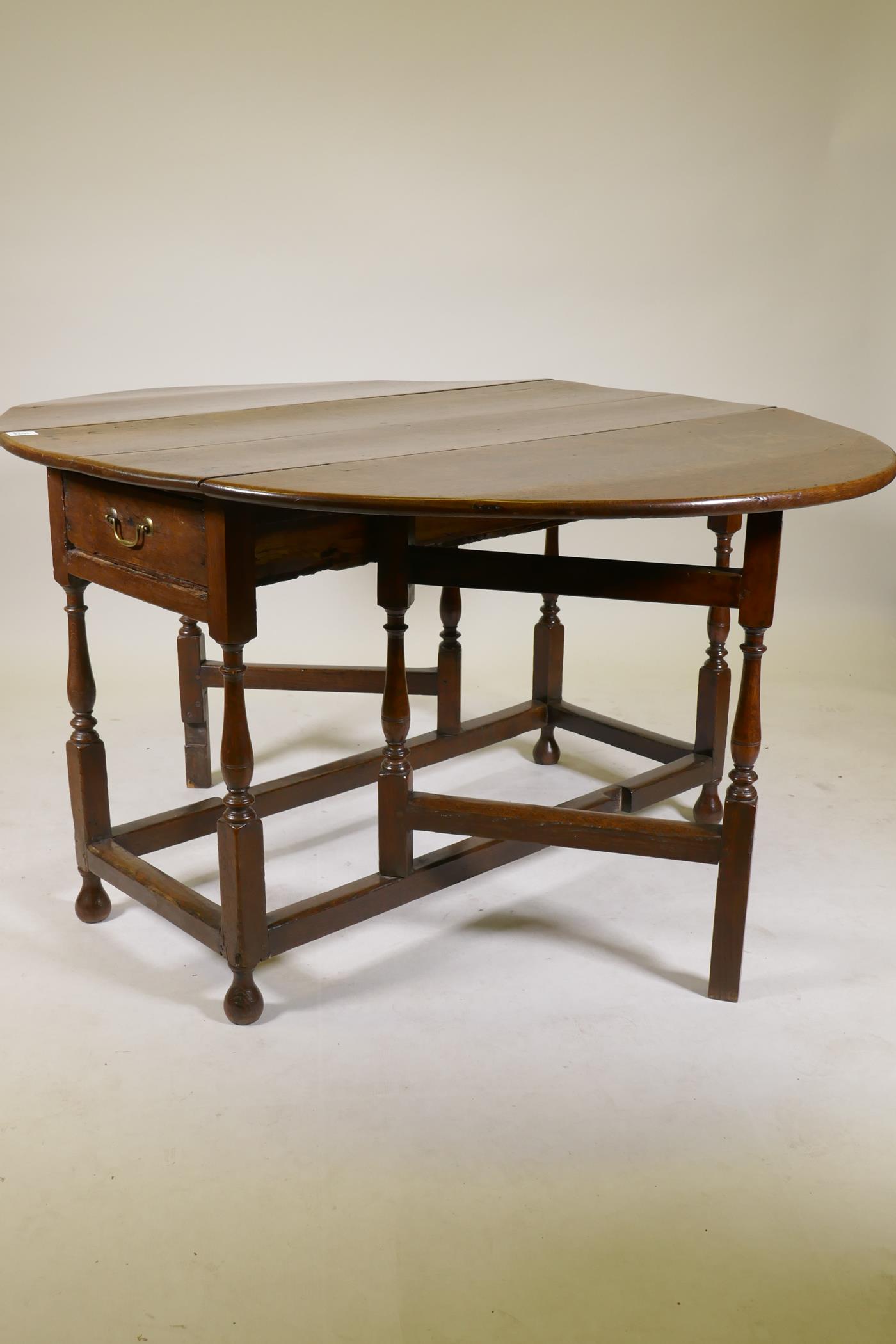 An C18th oak gateleg drop leaf table with single long drawer, raised on turned baluster shaped - Image 4 of 5