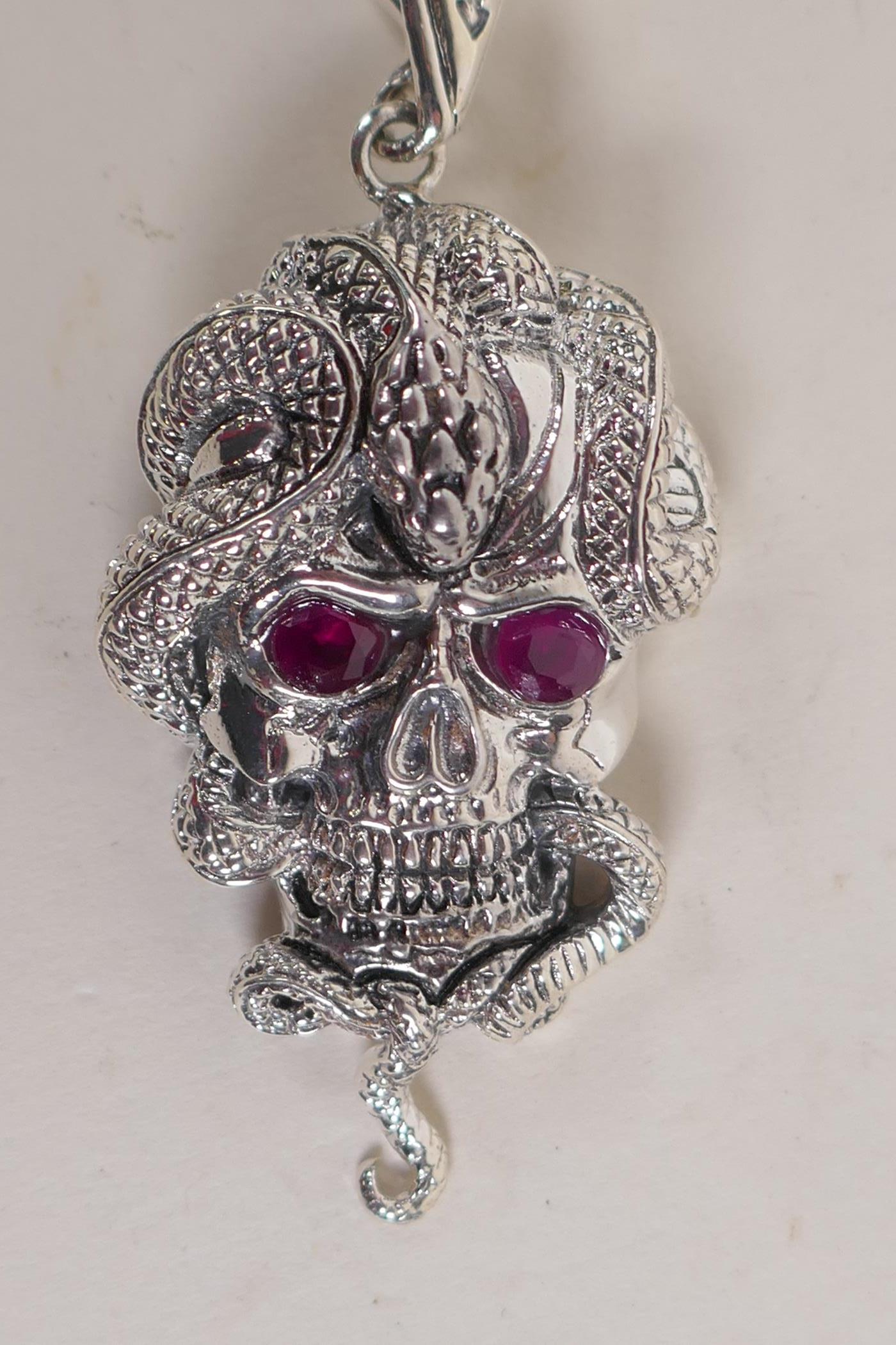 A silver 'snake and skull' pendant with stone set eyes, 2" long