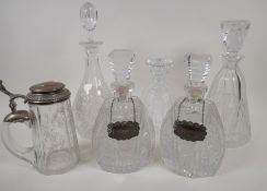 Five cut glass decanters, two with hallmarked silver spirit labels, and an engraved faceted glass