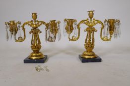 A pair of C19th two branch candelabra with pierced columns and lustre drops, lacking three, 13" high