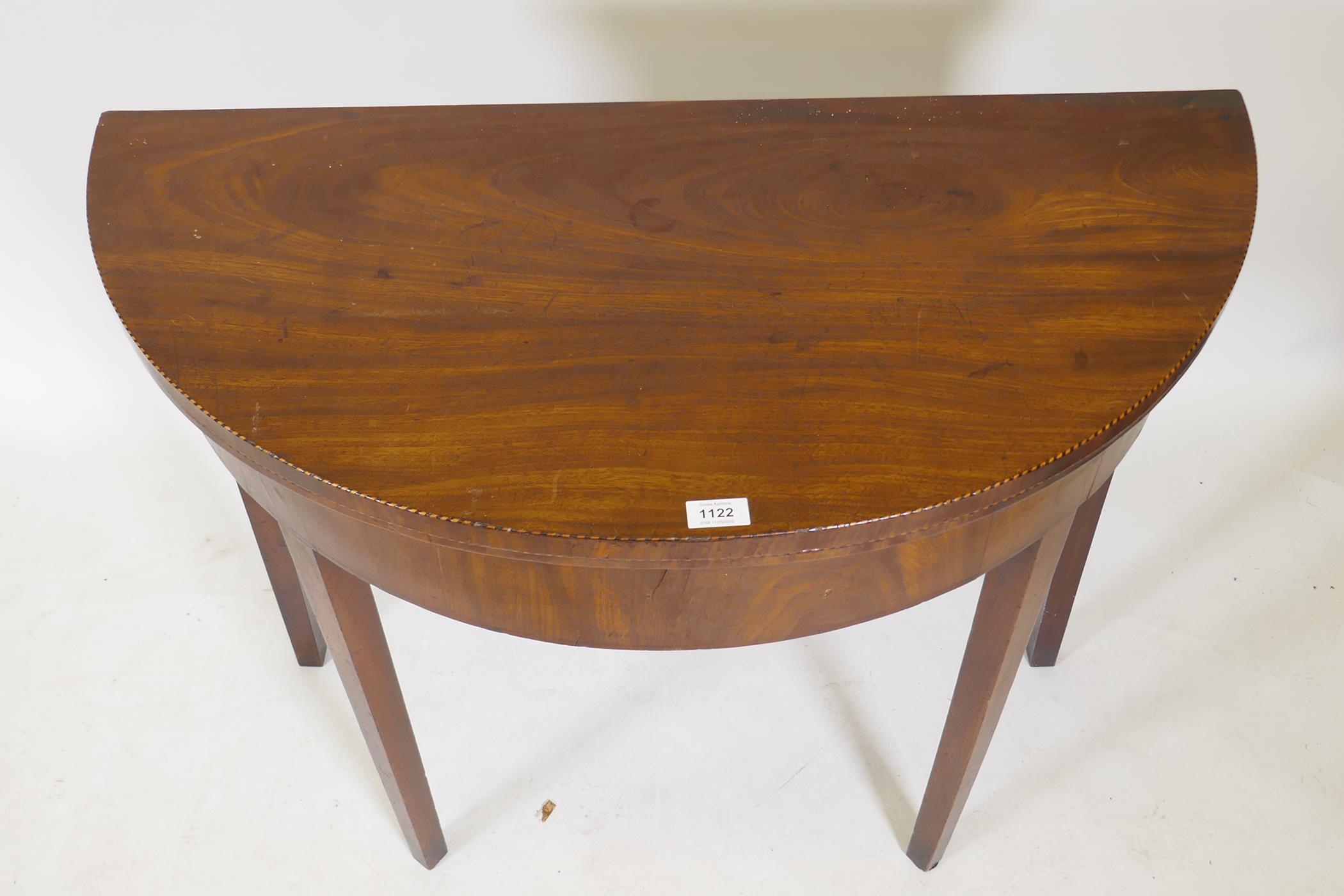 A Georgian mahogany fold over demi lune tea table with inlaid edges, raised on square tapering - Image 2 of 4