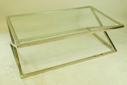 A contemporary glass topped coffee table on a chrome cross frame base, 55" x 31½" x 17½"