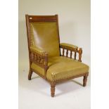 A Victorian walnut armchair with studded leather upholstery and open arms, raised on turned supports