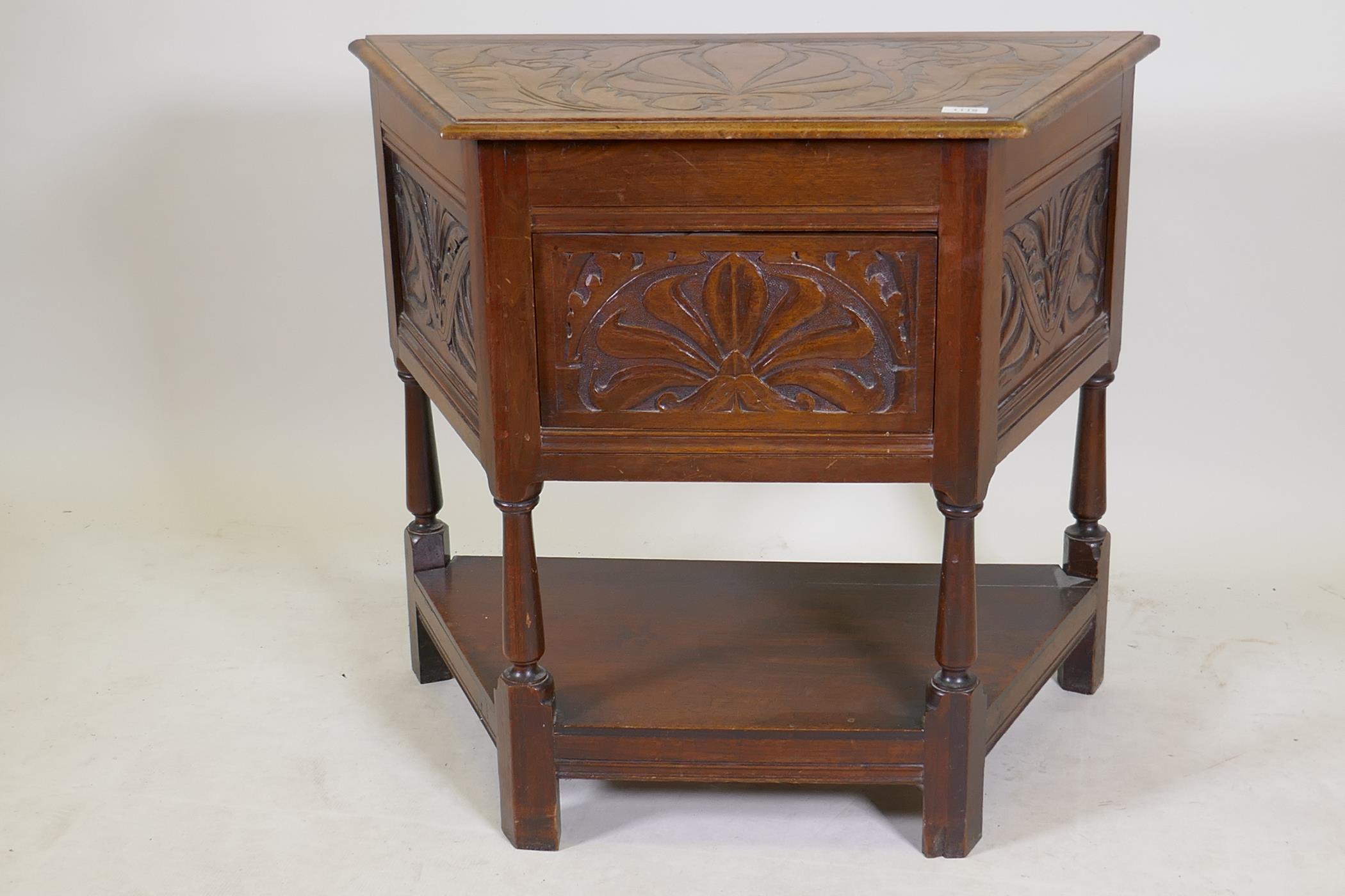 An early C20th walnut credence cabinet with carved panels and turned supports united by an
