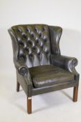 A Georgian style button back green leather wing armchair