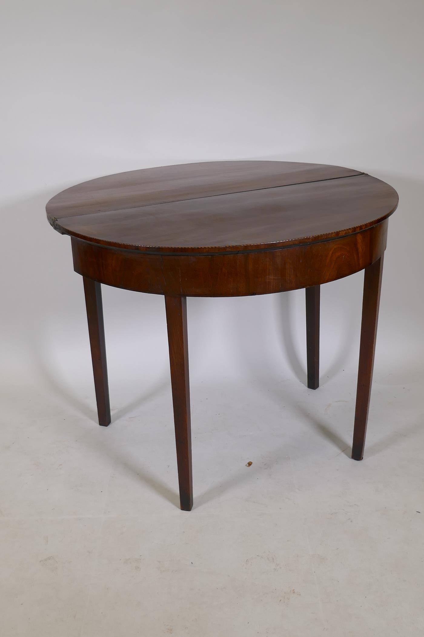 A Georgian mahogany fold over demi lune tea table with inlaid edges, raised on square tapering - Image 4 of 4