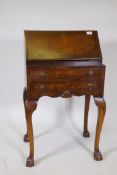 A 1920s Georgian style walnut fall front bureau with a fitted interior, two long drawers, cabriole