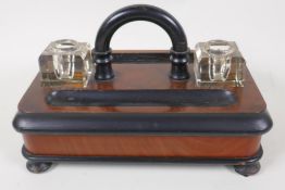 A C19th ebonised walnut desk standish with two glass inkwells and base drawer, inkwells lack covers,