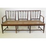 A C19th Hepplewhite style walnut settee, with shaped pierced splat back and caned seat, raised on