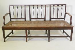 A C19th Hepplewhite style walnut settee, with shaped pierced splat back and caned seat, raised on
