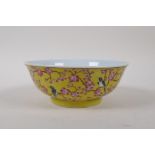 A polychrome porcelain bowl with bird and prunus blossom decoration on a yellow ground, Chinese