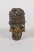 A brass vesta case in the form of a snake entwined skull, 5cm high