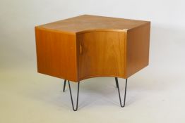 A G-Plan teak corner cupboard with rosewood top, and single concave door, raised on shaped metal