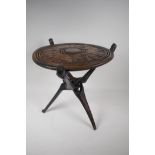 An African carved hardwood occasional table with reversible top on folding base, the top carved with
