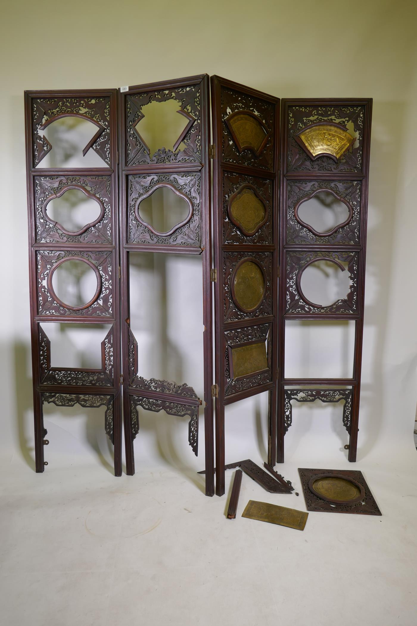 A Chinese hardwood four fold screen with fretwork panels and brass inset plaques, each panel 170 x