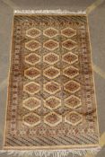 A gold ground wool Bokhara carpet, signed, 52" x 59", and an antique Persian cream ground wool rug