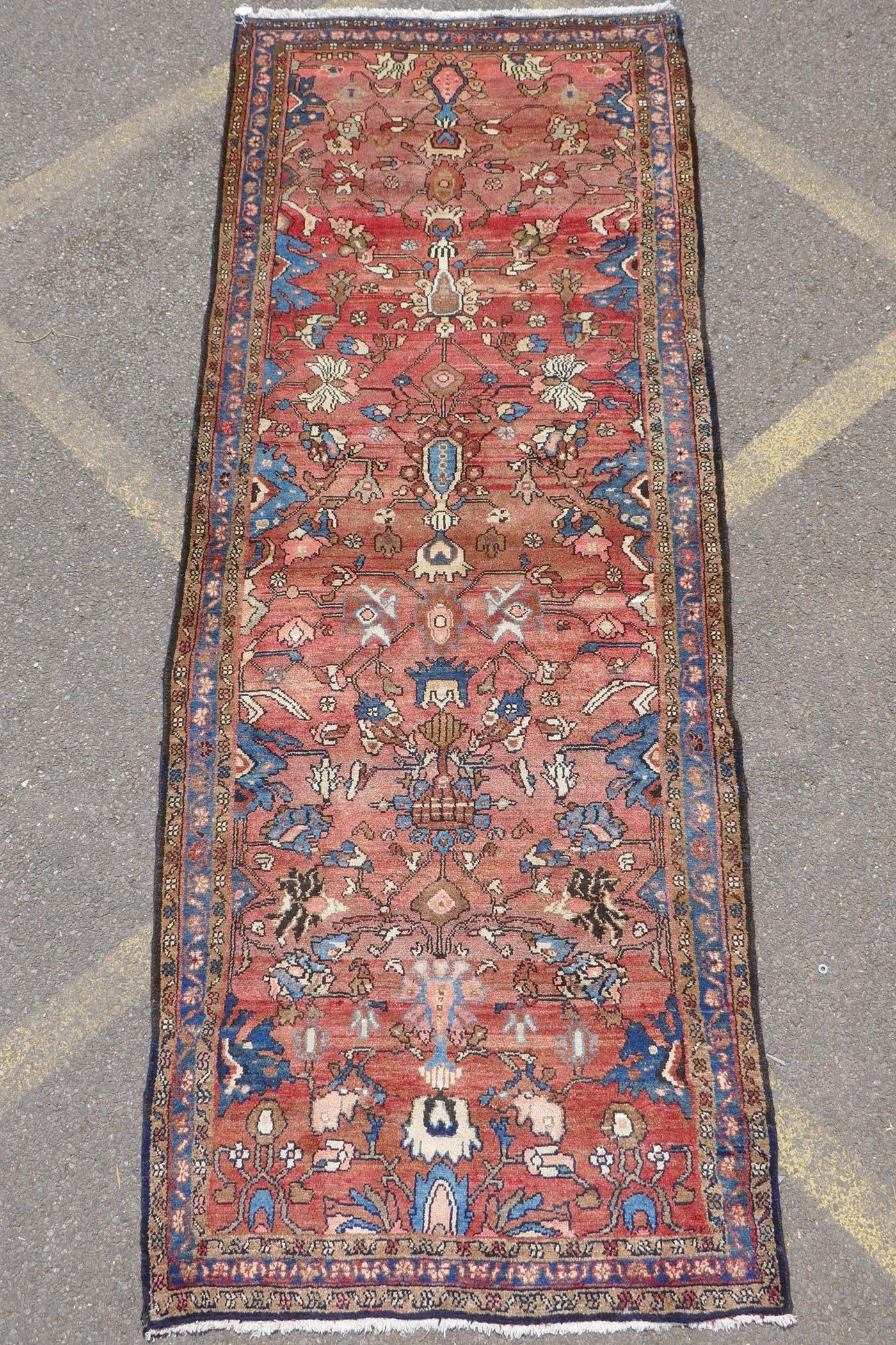 A washed terracotta ground Persian Hamadan runner, with all over floral pattern, 108cm x 284cm