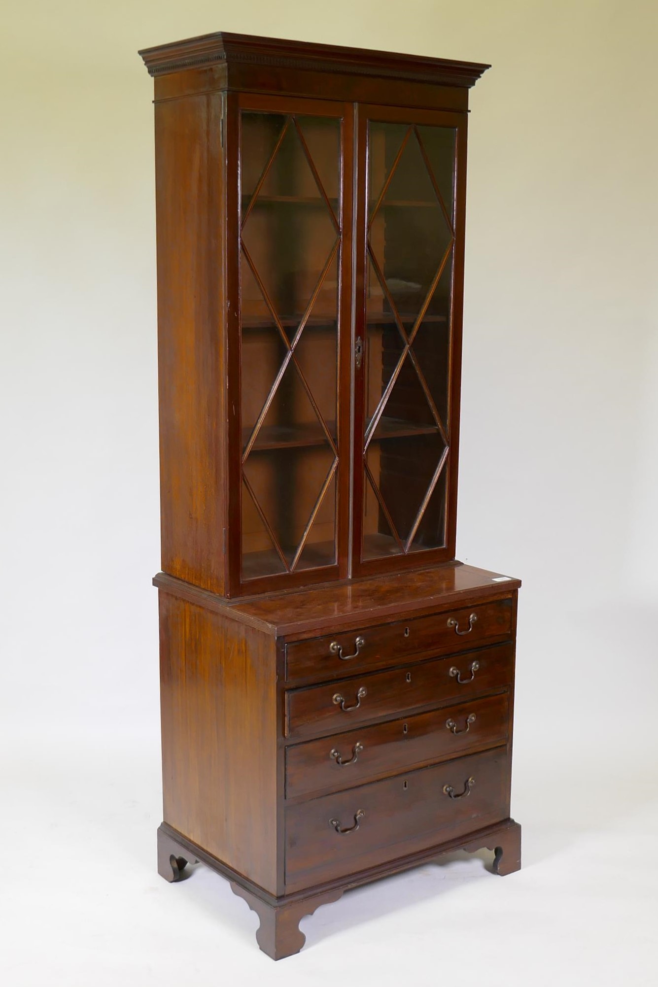 A small C19th mahogany bookcase with glazed top and base with reeded top over four oak lined drawers
