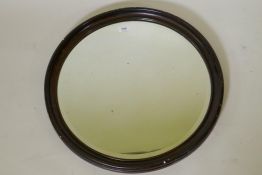 An early C20th circular wall mirror, with grained wood effect frame and bevelled glass, 65cm