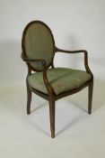 A Hepplewhite style elbow chair with spoon back and caned seat, raised on square tapering