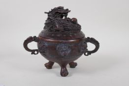 A Chinese bronze two handled censer and cover on tripod supports, with dragon decoration, 16cm high