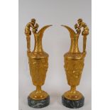 A pair of ormolu ewers with satyr handles and raised Bacchanalian frieze, mounted on marble bases