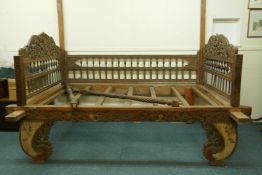 A C19th Indian hardwood bed, with carved panel ends raised on shaped supports with painted