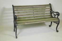 A cast iron garden bench with scrolled ends and lion mask decoration, and teak slats, 127cm long