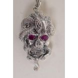 A white metal 'snake and skull' pendant with stone set eyes, 2" long