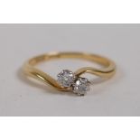 An 18ct yellow gold two stone diamond cross over ring, approx 30 points, size R