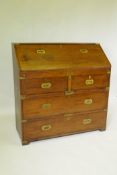 An Anglo Indian teak campaign fall front bureau with fitted interior and inset brass handles, in two