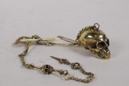 A polished brass Albert style watch chain with skull and bones decoration, 31cm long