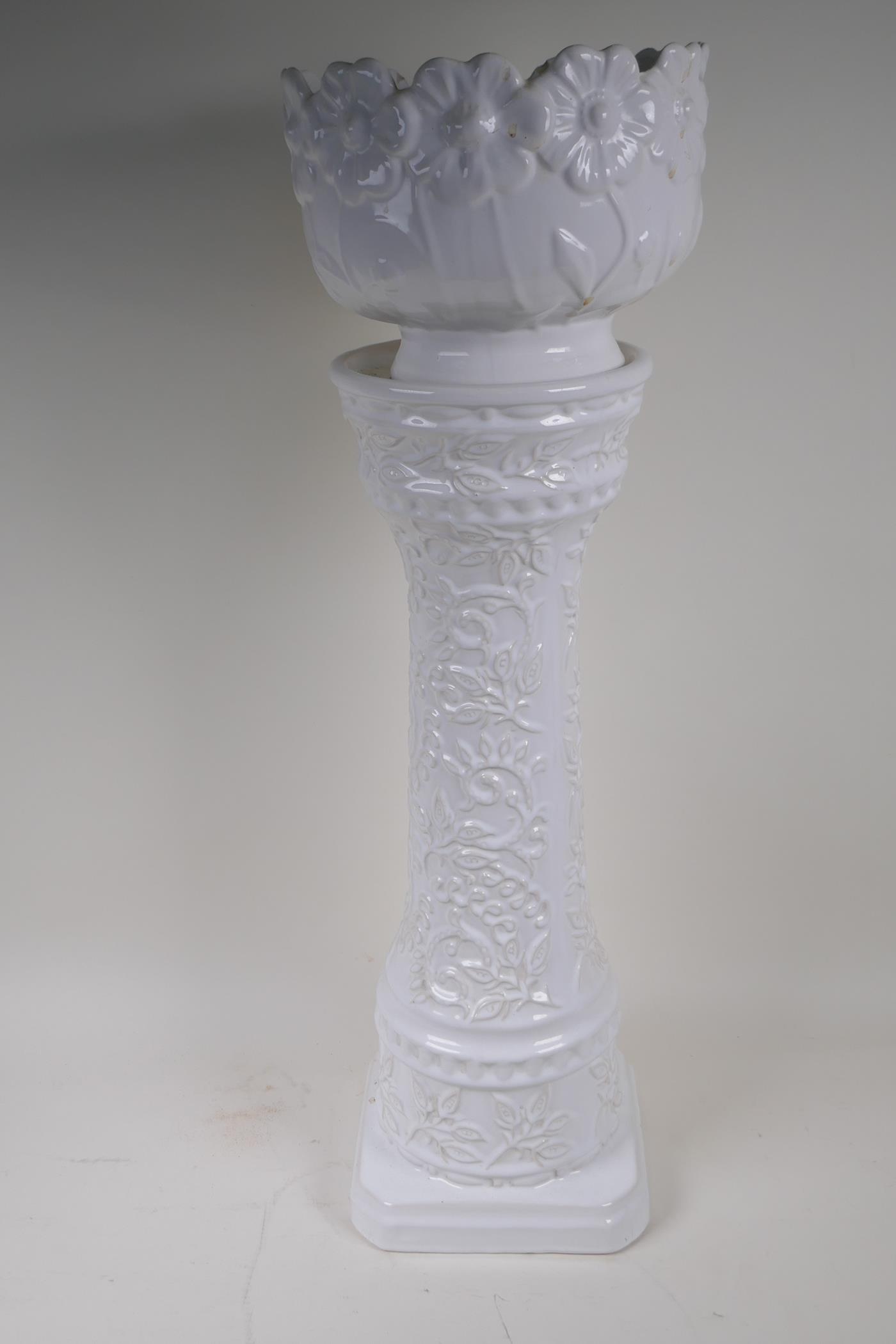 A German white glazed pottery jardiniere on stand with embossed flower and vine decoration, 67cm