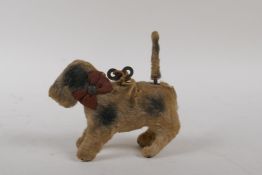 A 1930s wind up waggle tail tinplate dog with fabric covering, 10cm long