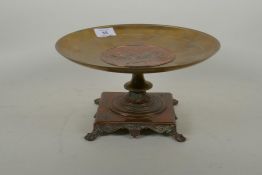 An antique copper and brass tazza, the inset plaque with raised classical design, 27cm diameter,
