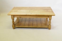 A stripped pine two tier coffee table, raised on baluster shaped supports, 122 x 75 x 45cm