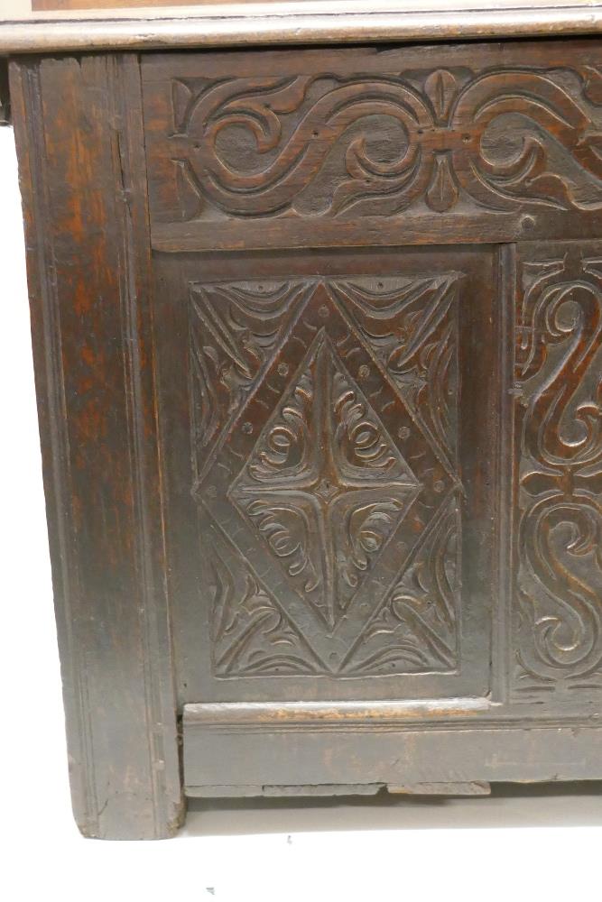 An C18th oak coffer with plank top and carved triple panel front, raised on stile supports, 49" x - Image 2 of 2