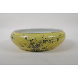 A Chinese yellow glazed porcelain dish with rolled rim, with black and white floral decoration, mark