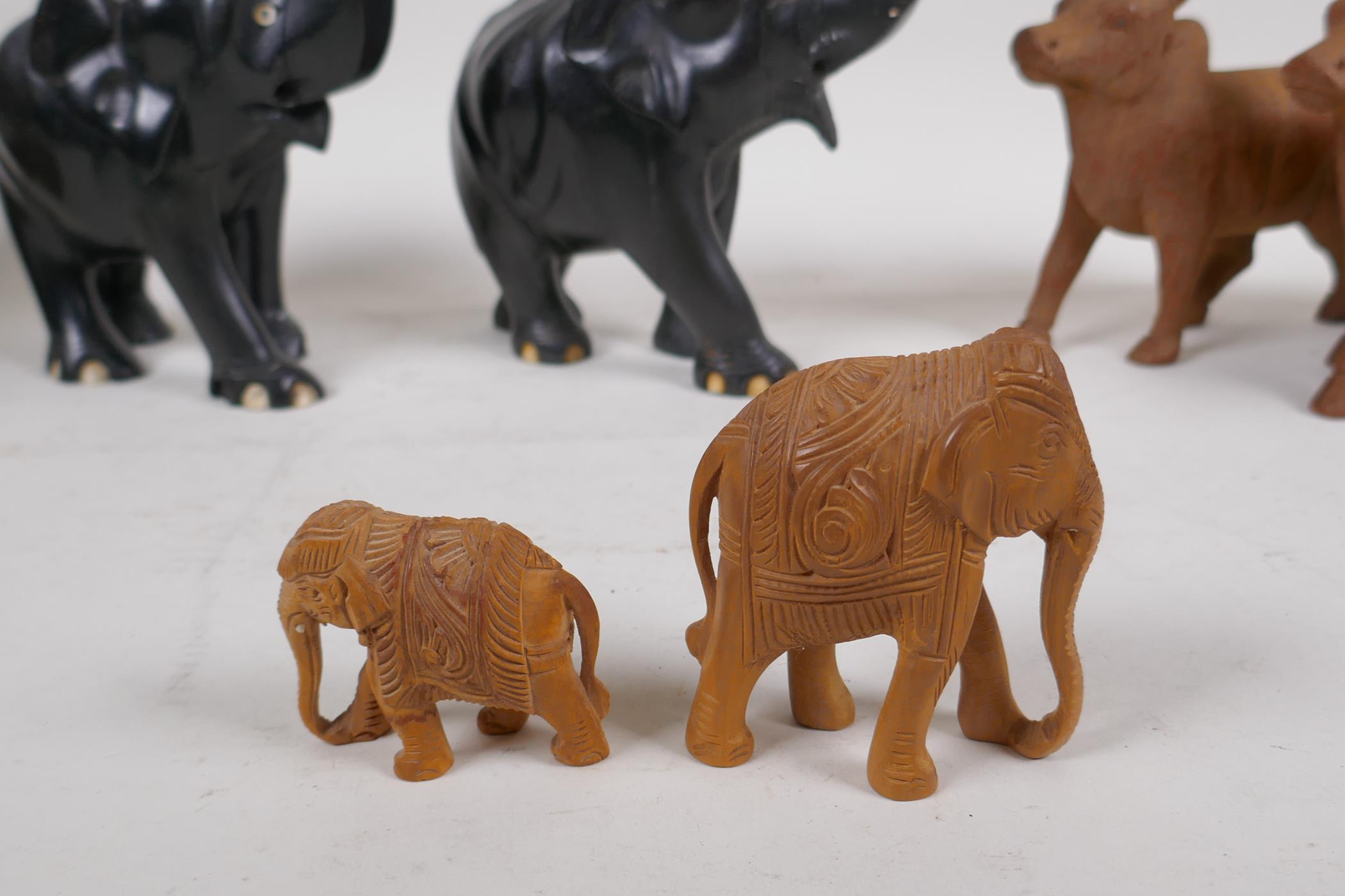 A collection of Indian carved wood animals including a pair of ebony elephants, cows etc, largest - Image 5 of 5