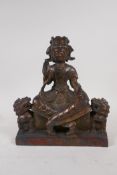 A Sino Tibetan gilt bronze figure of a deity seated on a throne, flanked by fo dogs, 23cm high