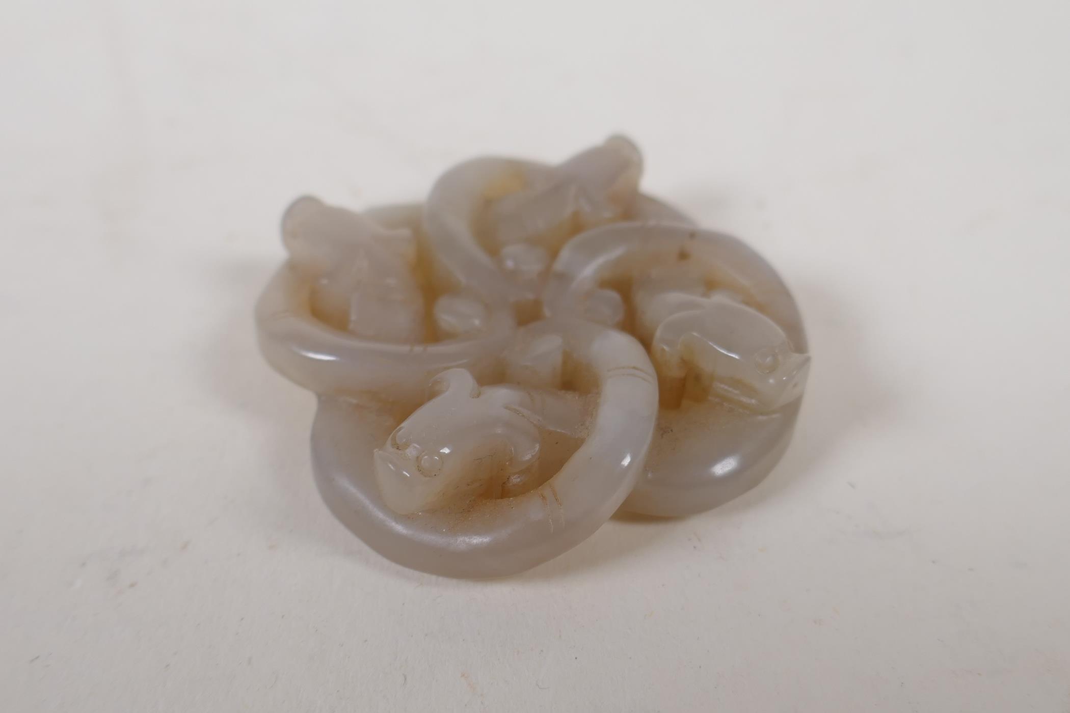 A Chinese grey jade pendant carved in the form of entwined dragons, 5cm x 5cm