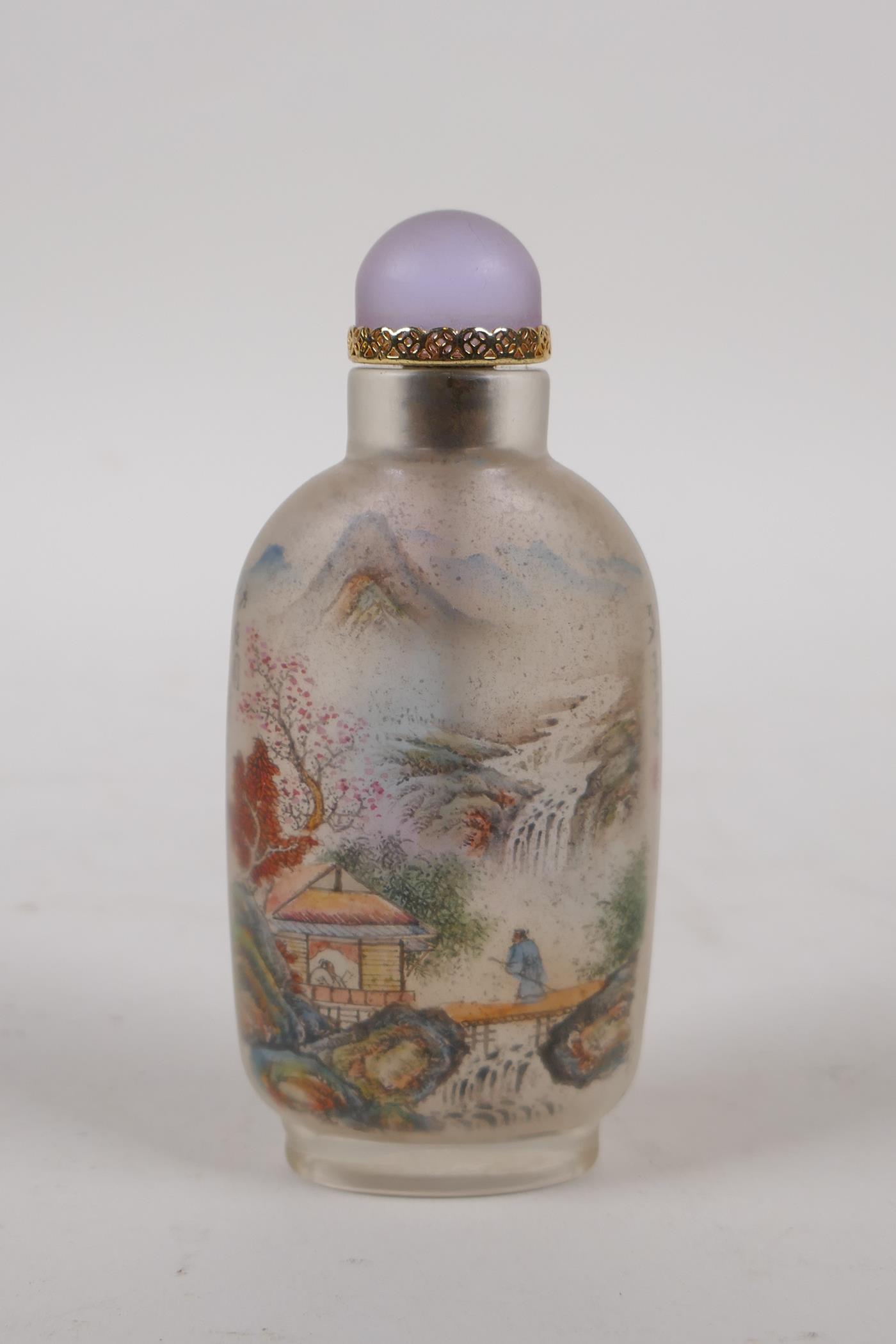 A Chinese reverse decorated glass snuff bottle depicting a riverside landscape and objects of