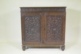 A C19th Anglo Indian padouk side cabinet with carved frieze and doors, raised on shaped supports,