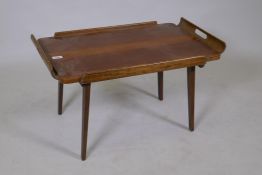 A mid century walnut serving tray with moulded handles and fold down supports, 46 x 72 x 40cm