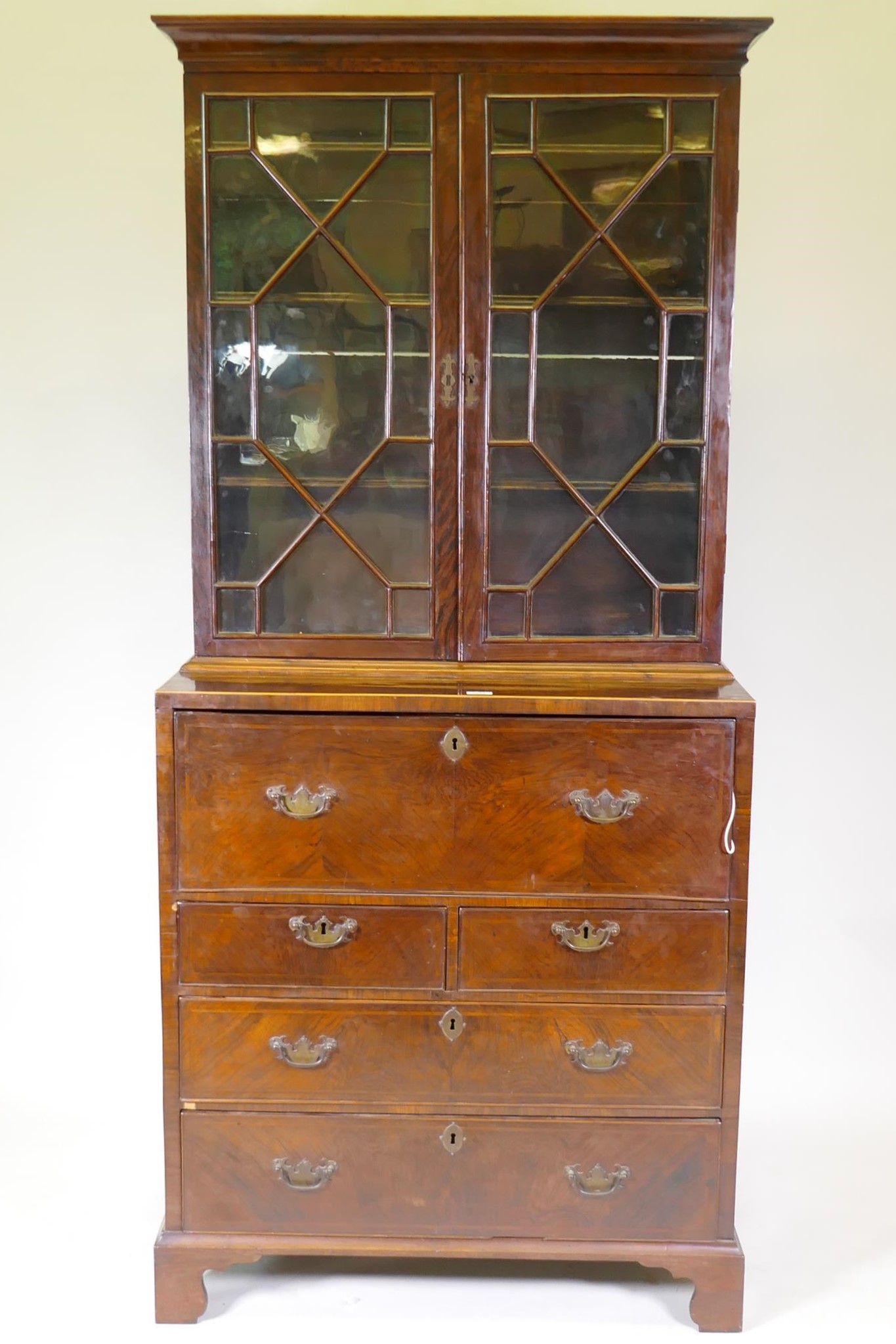 A C19th figured walnut secretaire bookcase, the astragal glazed upper section with adjustable