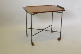 A mid century rosewood serving tray with ebonised handles, raised on folding metal stand with