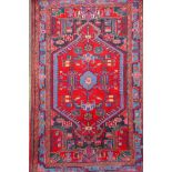 A Persian red ground wool rug with a multicolour geometric medallion design, 33" x 52"