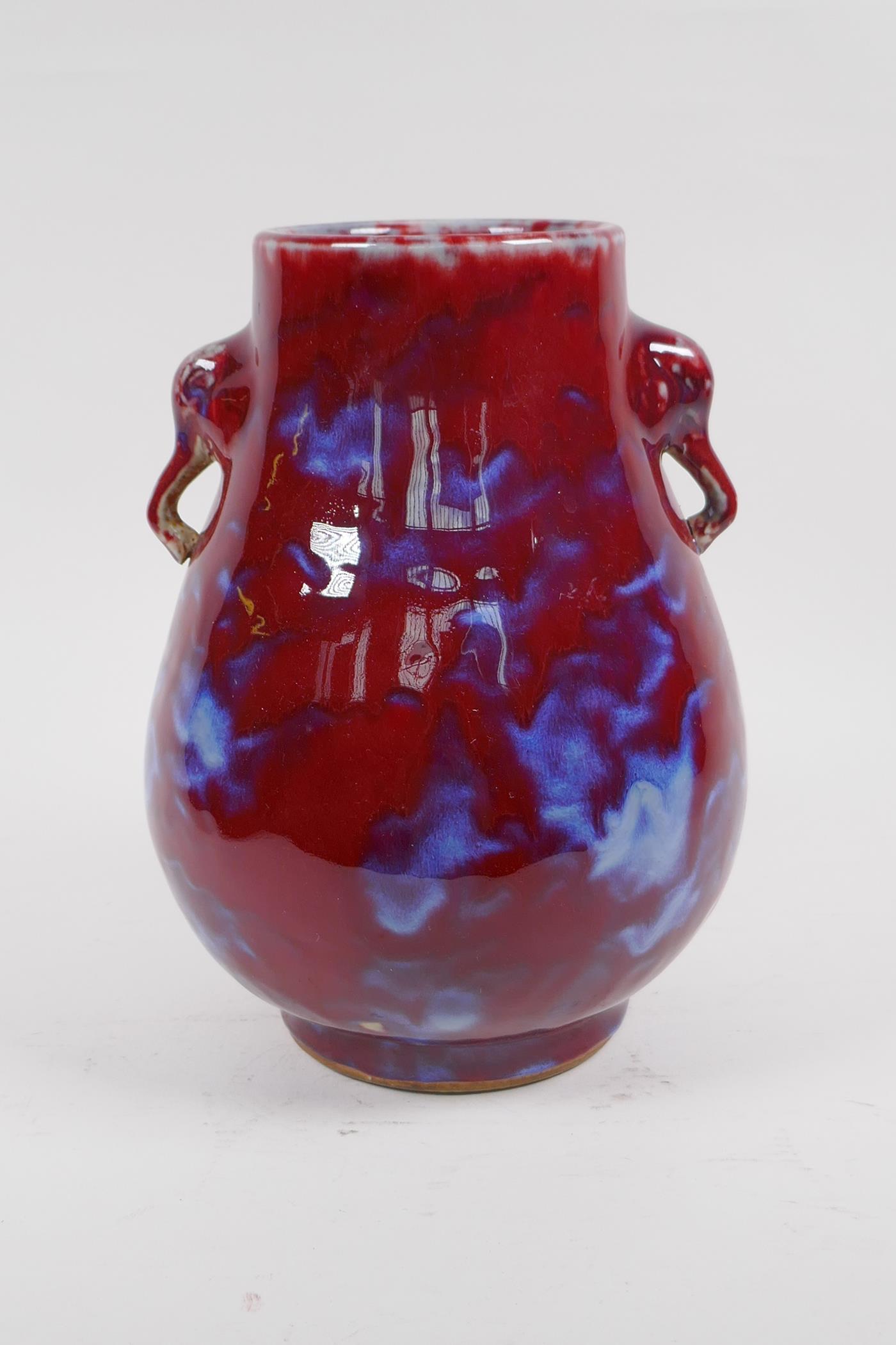A Chinese blue and red flambe glazed porcelain vase with two elephant mask handles, 27cm high